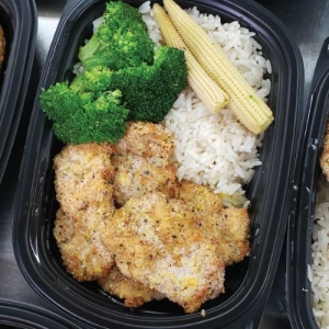 Oven baked breaded chicken breast with lemon sauce served with rice and vegetables