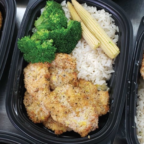 Oven baked breaded chicken breast with lemon sauce served with rice and vegetables